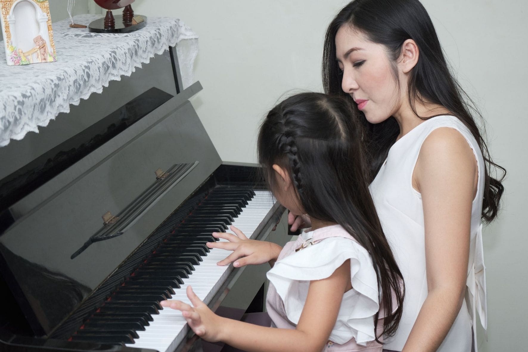 Dozentin zeigt einer Schülerin das Klavierspielen